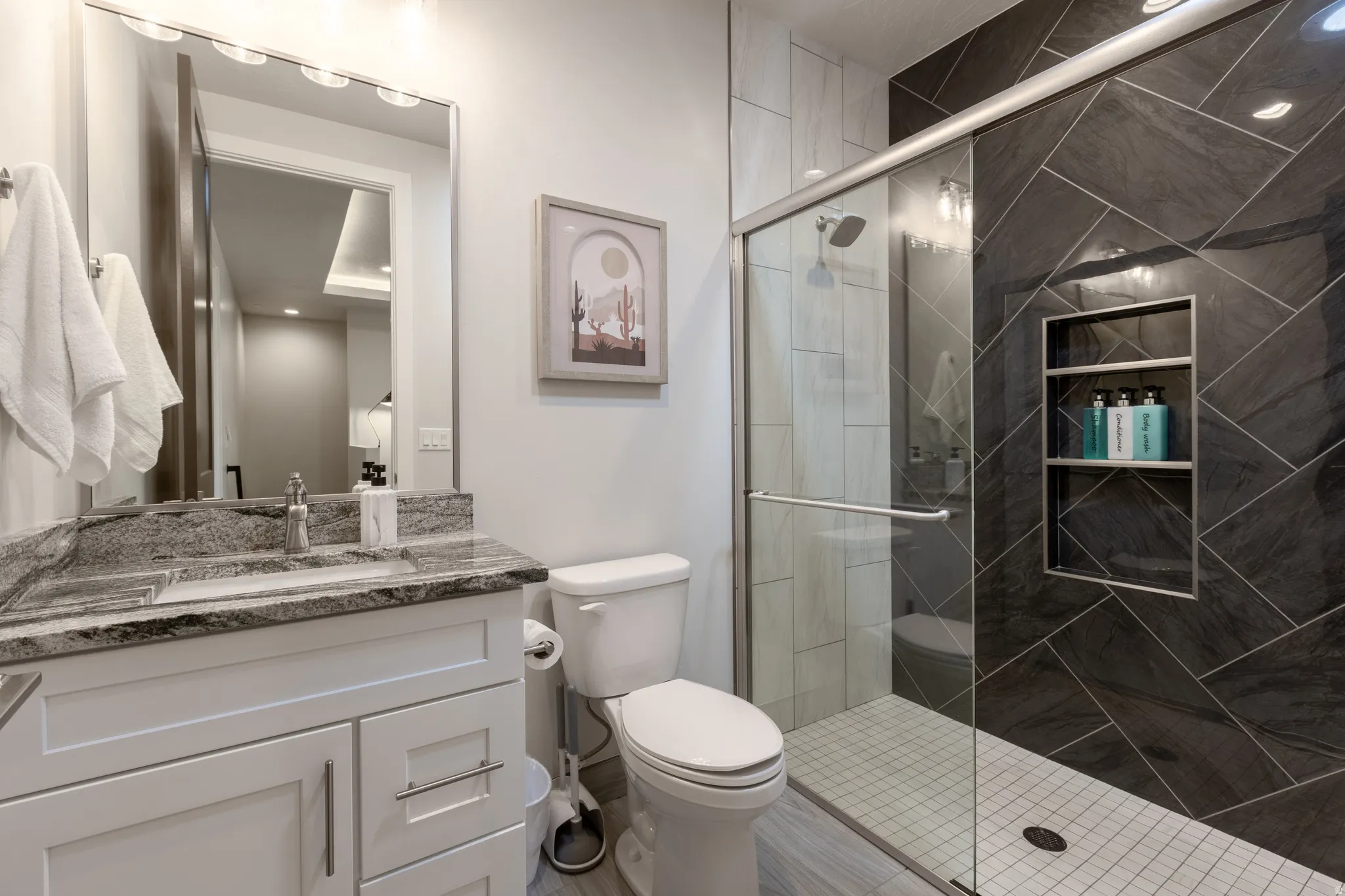 Full bathroom featuring a white vanity with a stone countertop, an undermount sink, and a framed mirror with overhead lighting