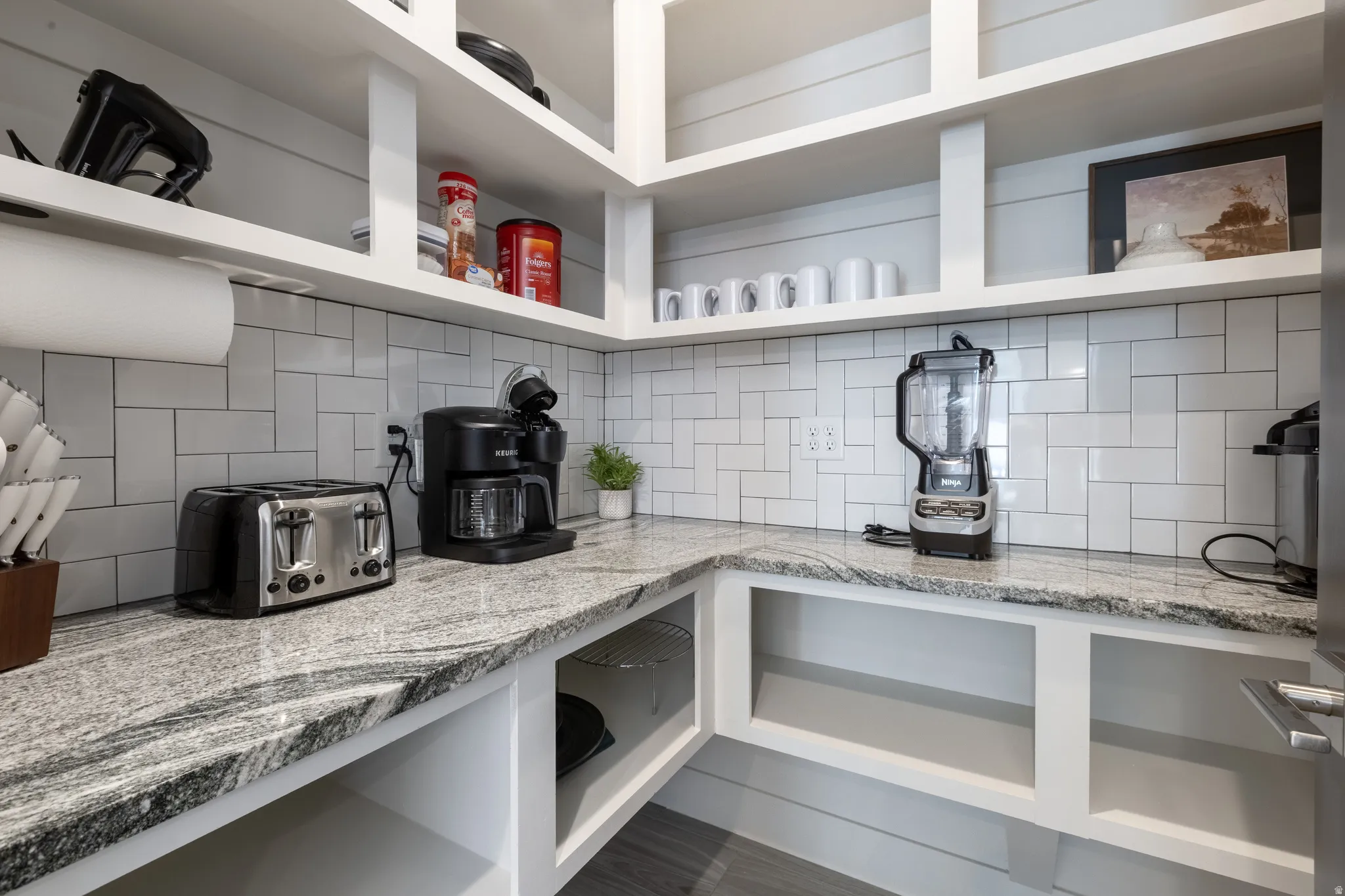 Kitchen pantry featuring extensive open shelving, durable countertops, and subway tile backsplash