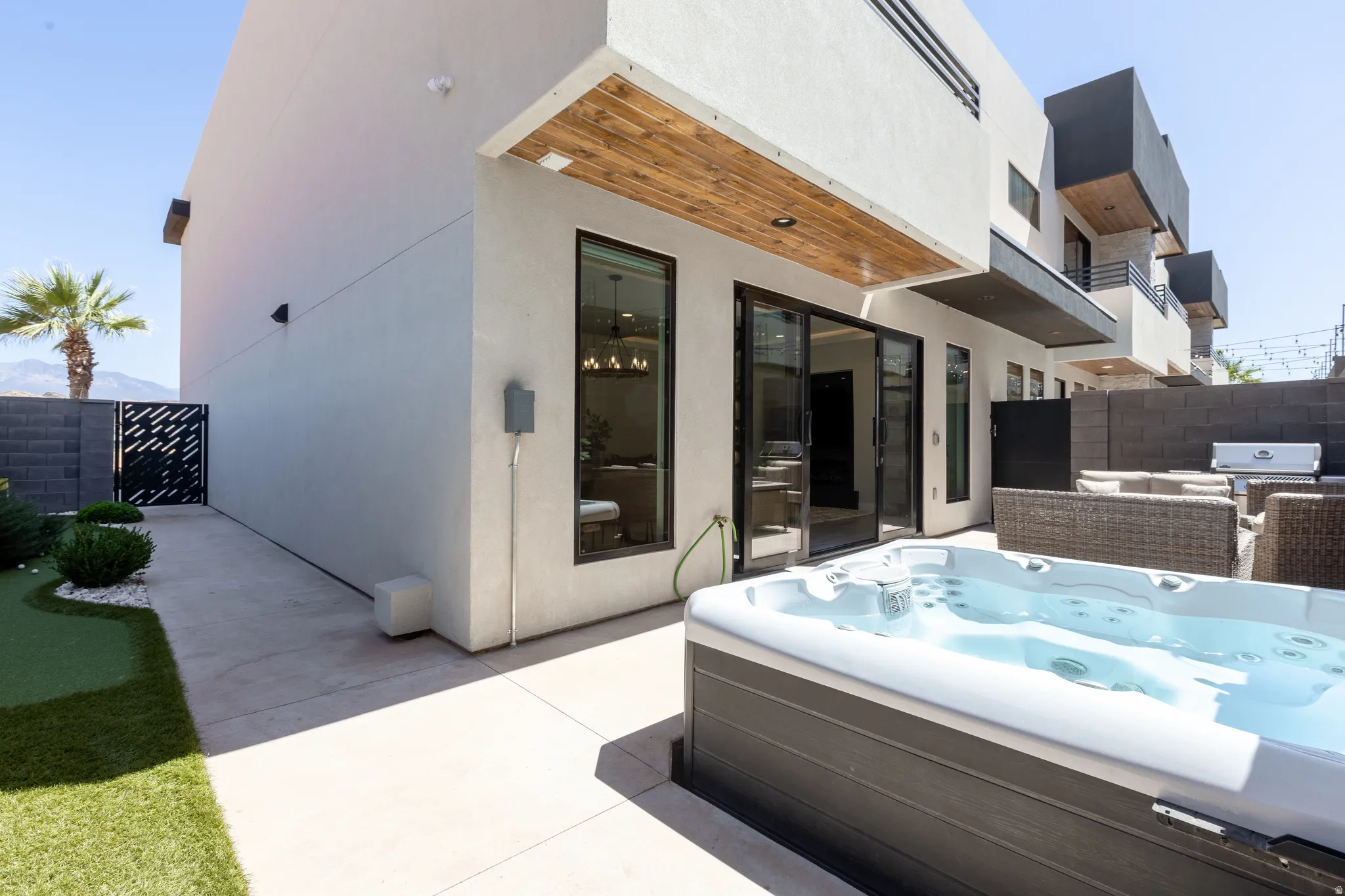 Patio featuring a built-in spa, concrete surfacing, and artificial turf landscaping