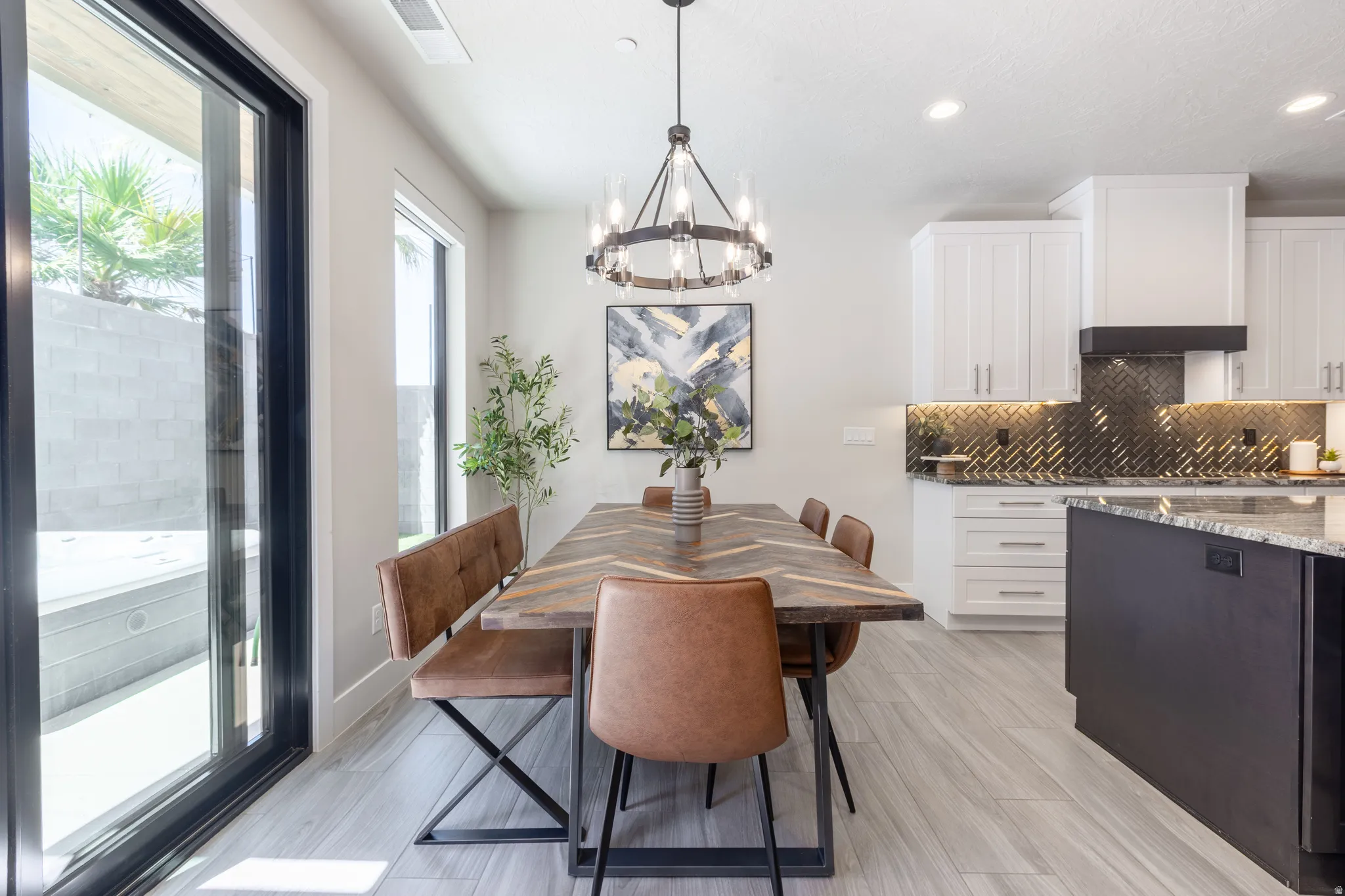Open-concept dining area featuring wood-finish flooring, a contemporary chandelier, and a large sliding glass door