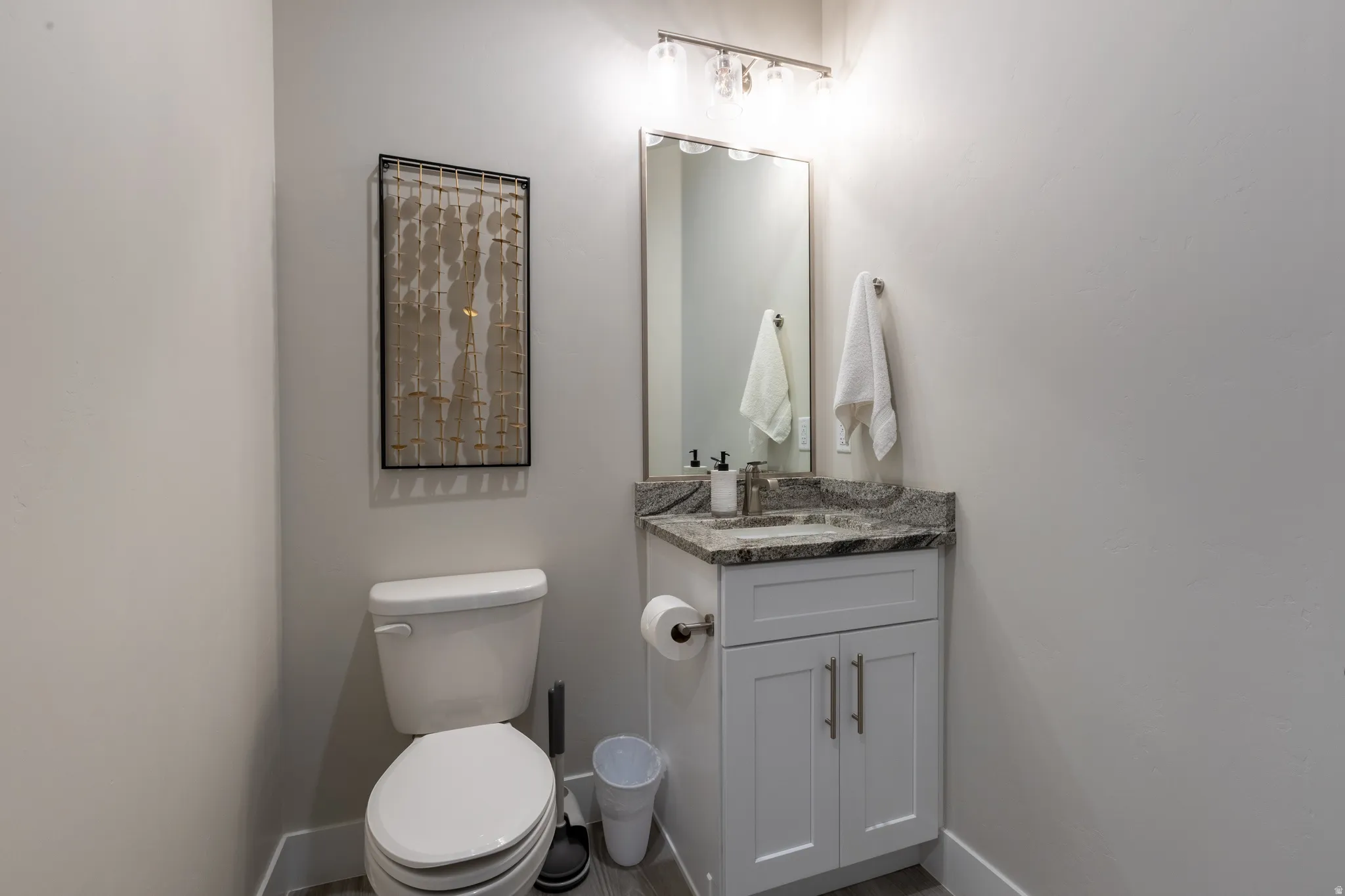 Powder room with a white vanity featuring a granite countertop, undermount sink, and brushed nickel hardware