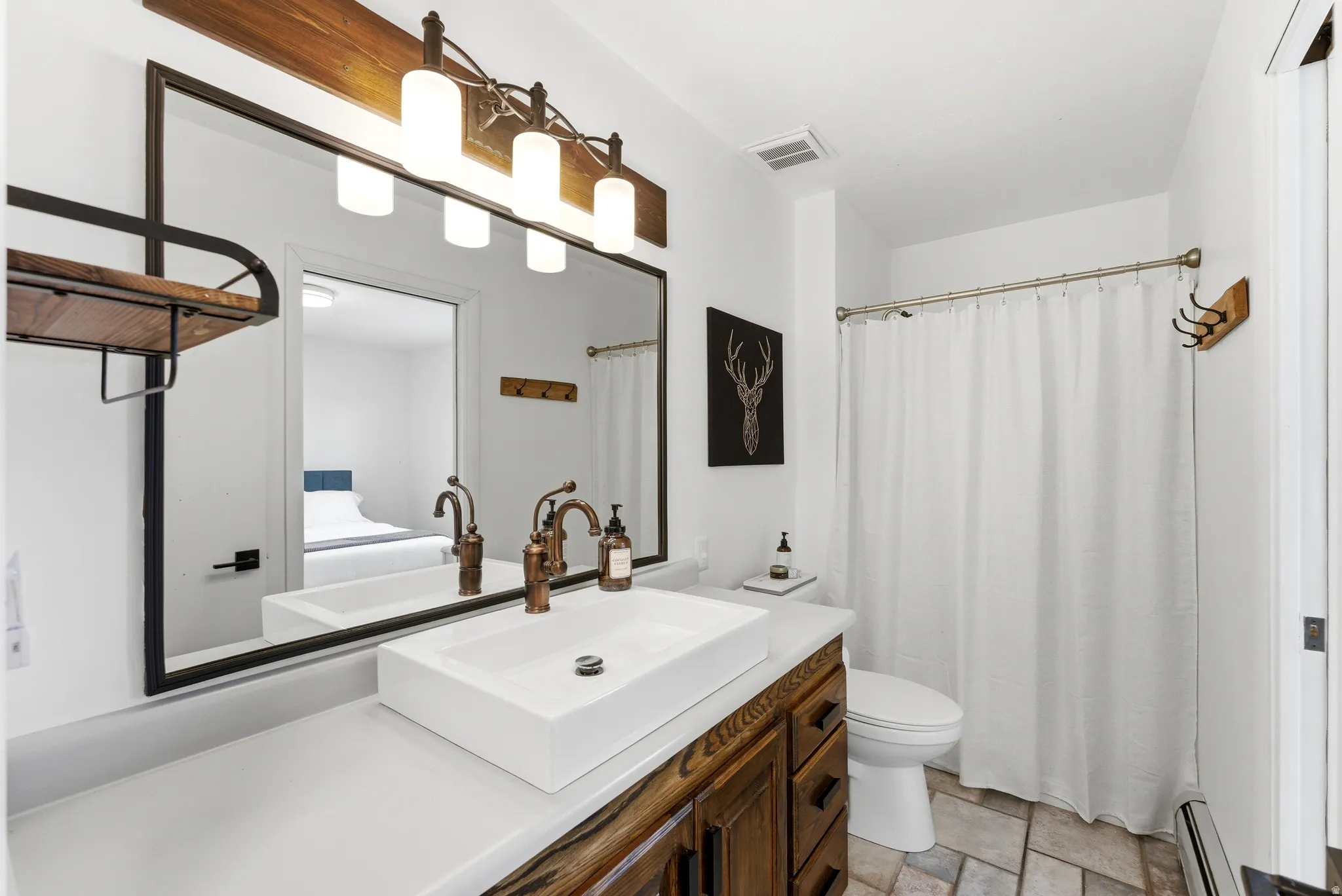 Bathroom featuring a wide vanity with a rectangular vessel sink, bronze-finish fixtures, and a large wall-mounted mirror