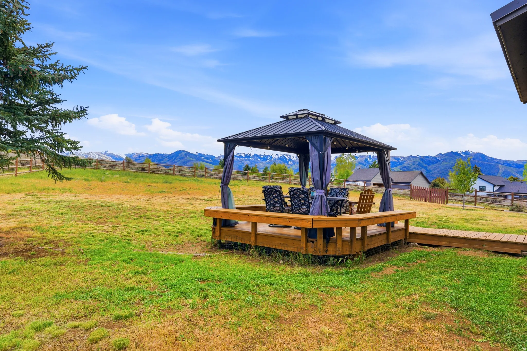Spacious outdoor living area with a dark metal gazebo on a wood-finish deck