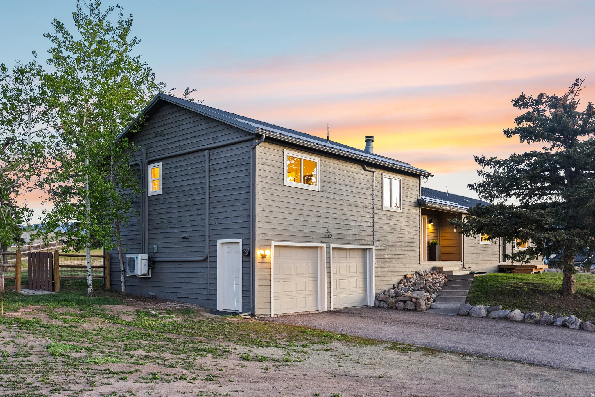 Contemporary exterior featuring two-tone siding, a metal roof, and a two-car garage