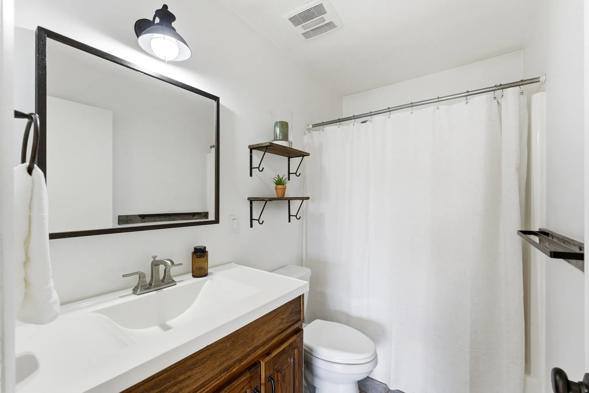 Bathroom with a wood-finish vanity, integrated white sink, and brushed nickel faucet