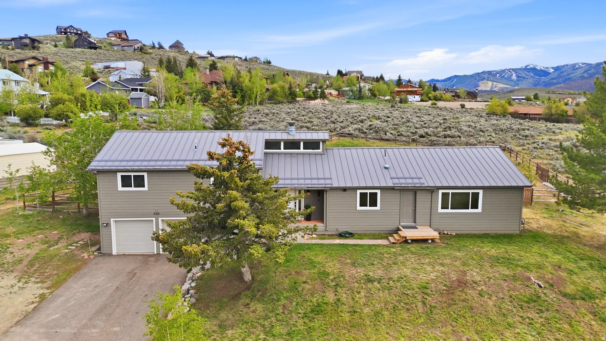 Contemporary home featuring a gray siding exterior, a gray metal roof, and a two-car garage