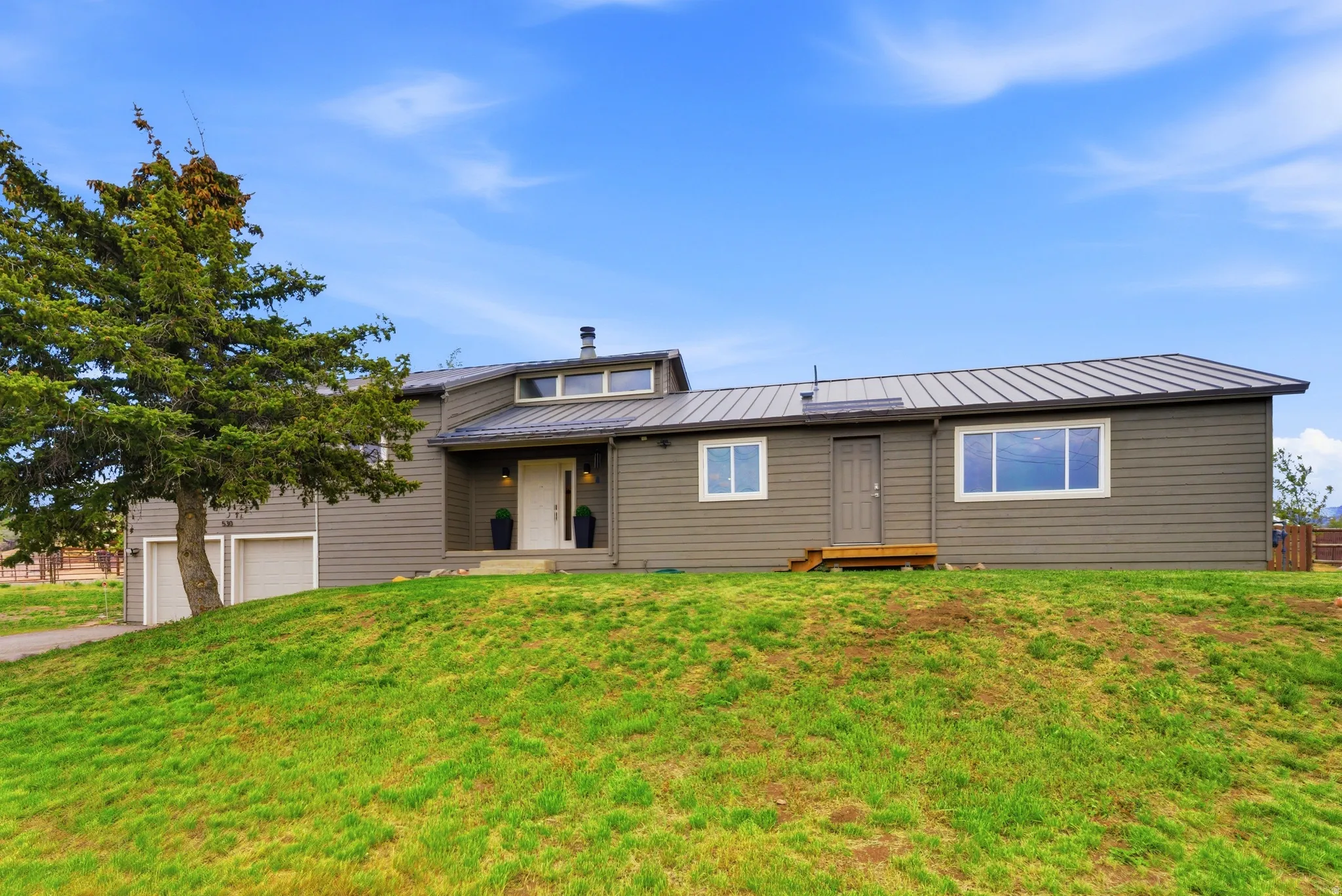 Contemporary-style residence featuring horizontal siding, a metal roof, and a prominent white entry door