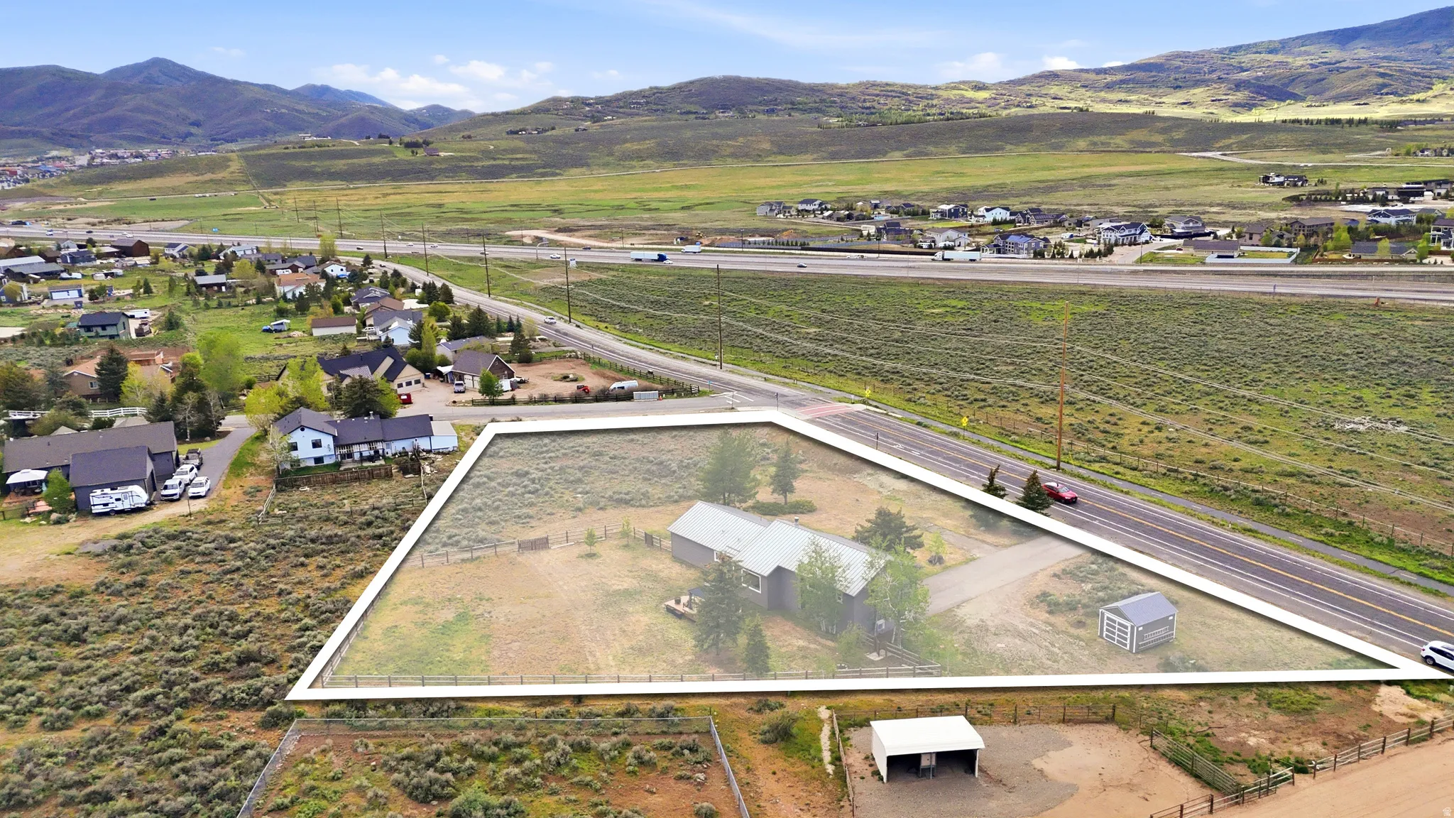 Expansive triangular-shaped parcel featuring a single-story residence with a light-colored roof, a detached storage shed, and a fenced perimeter