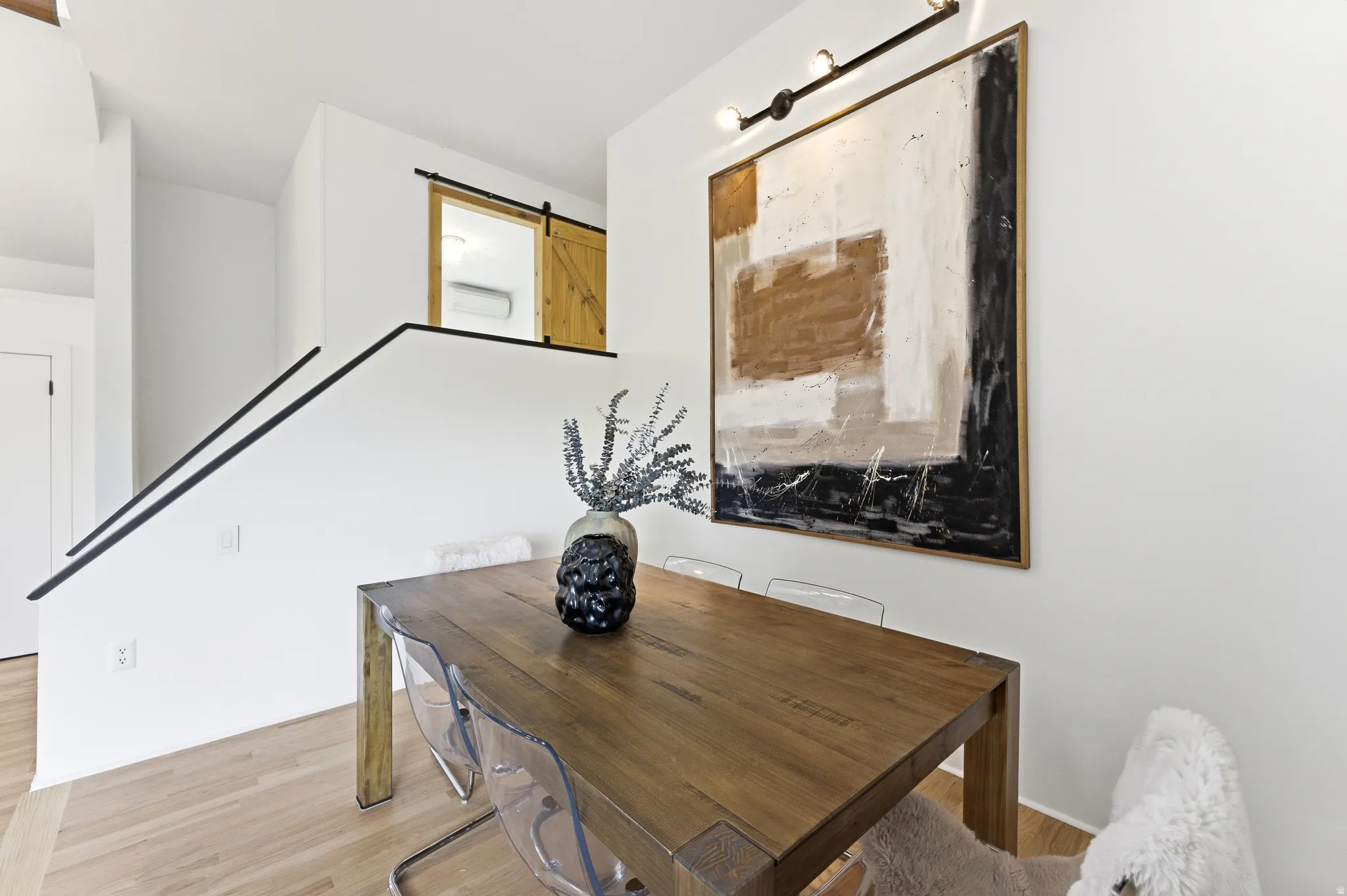 Open-concept dining area featuring light wood-finish flooring and a contemporary black metal handrail