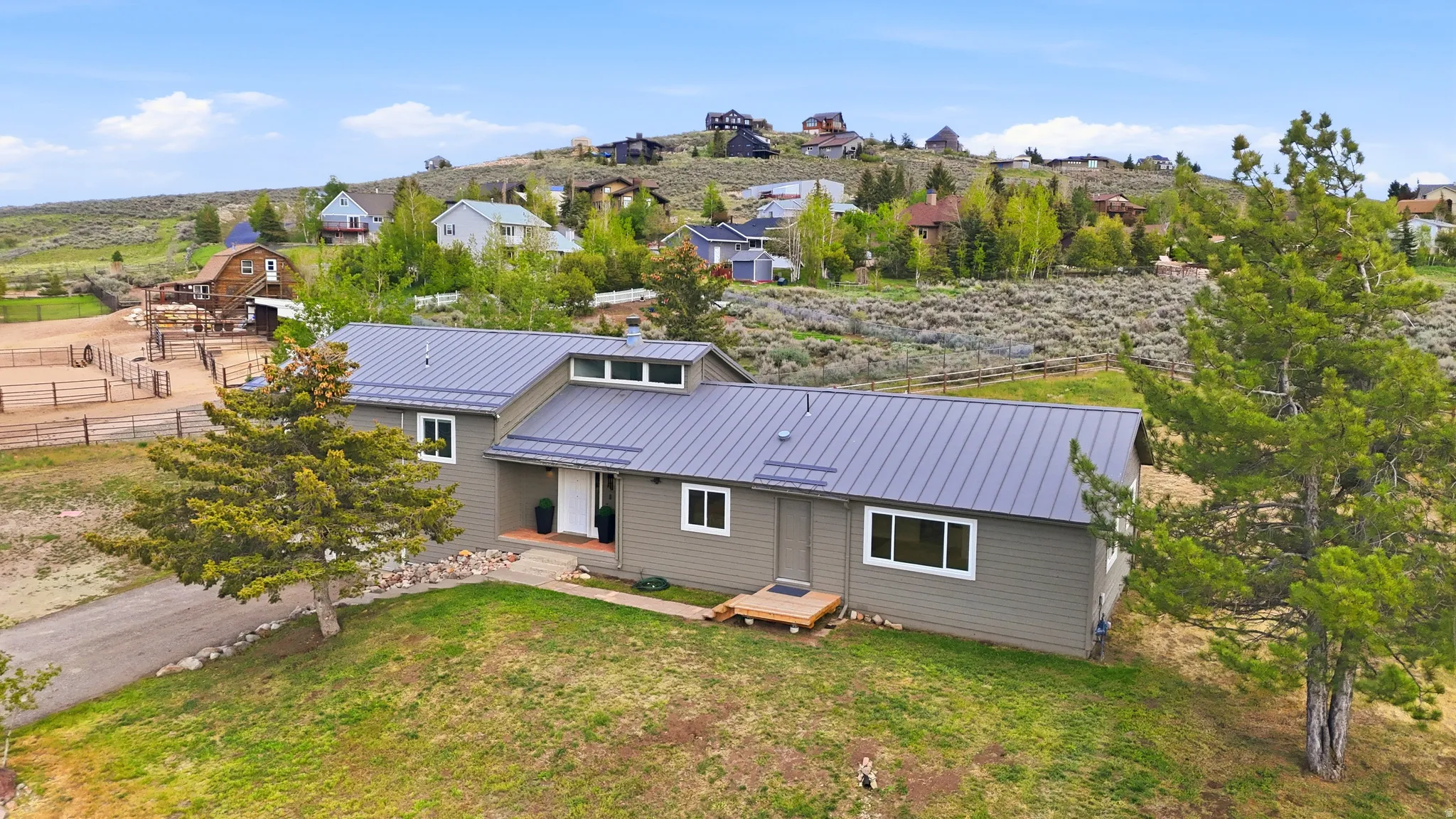 Contemporary ranch-style residence featuring a gray metal roof and light gray siding