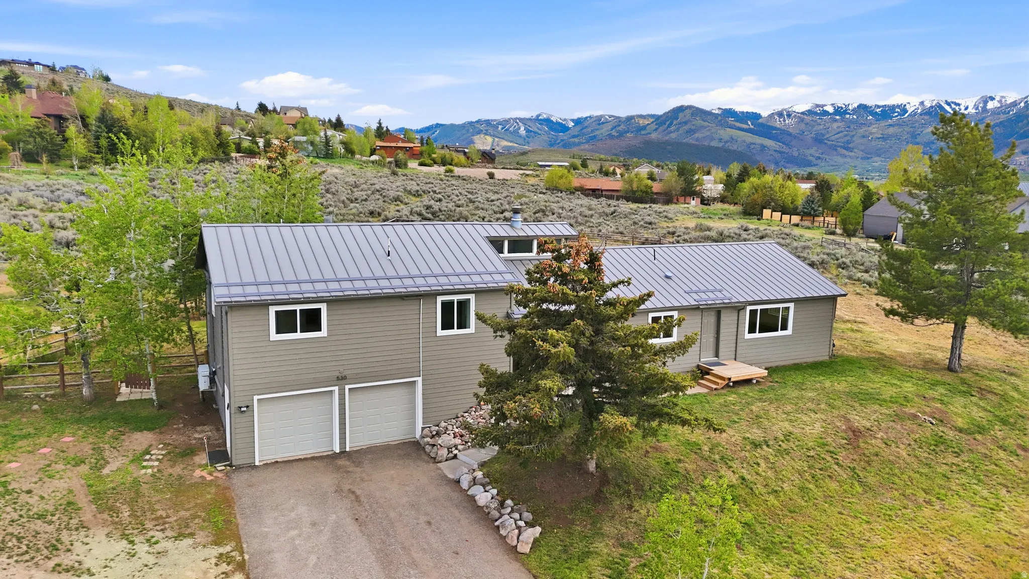 Contemporary home featuring a gray metal roof, light green siding, and white window frames
