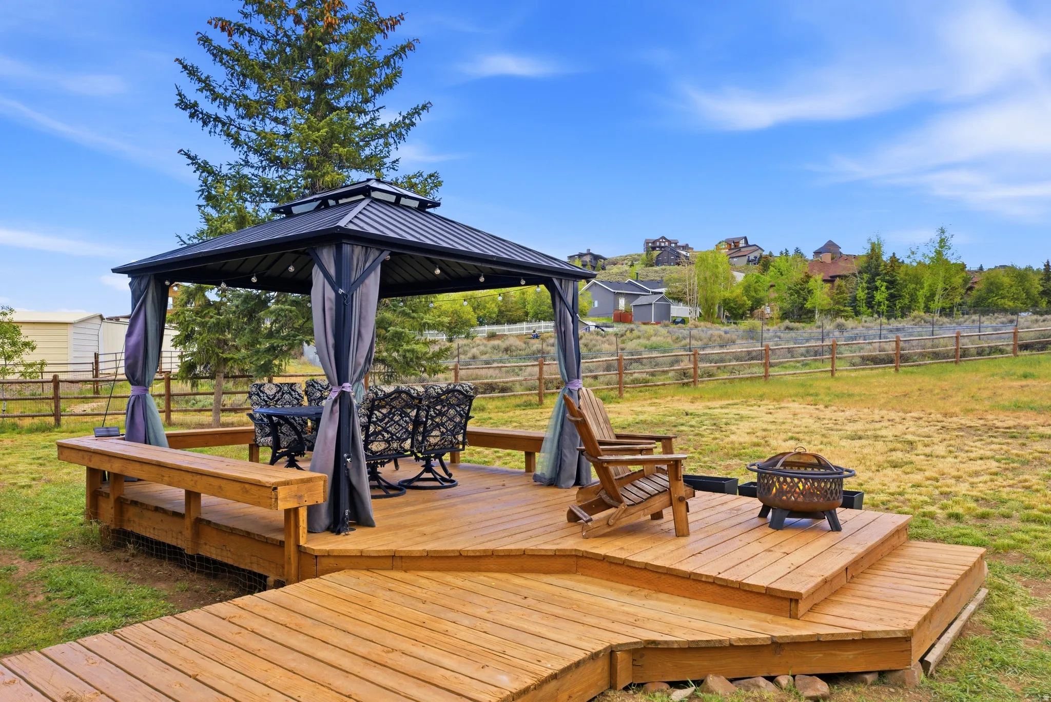 Multi-level wood deck featuring an integrated bench and a gazebo with fabric drapery