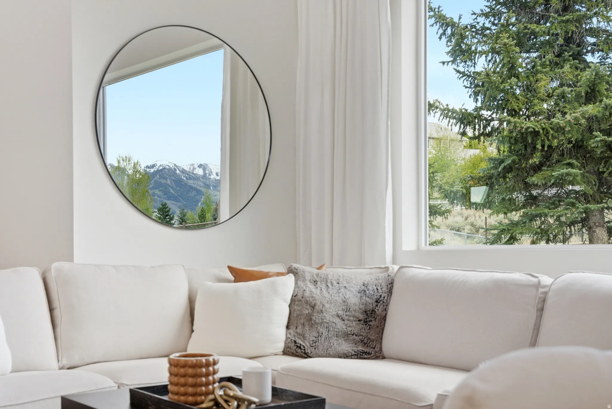 Spacious interior featuring a large wall-mounted circular mirror, bright white walls, and substantial windows with white trim