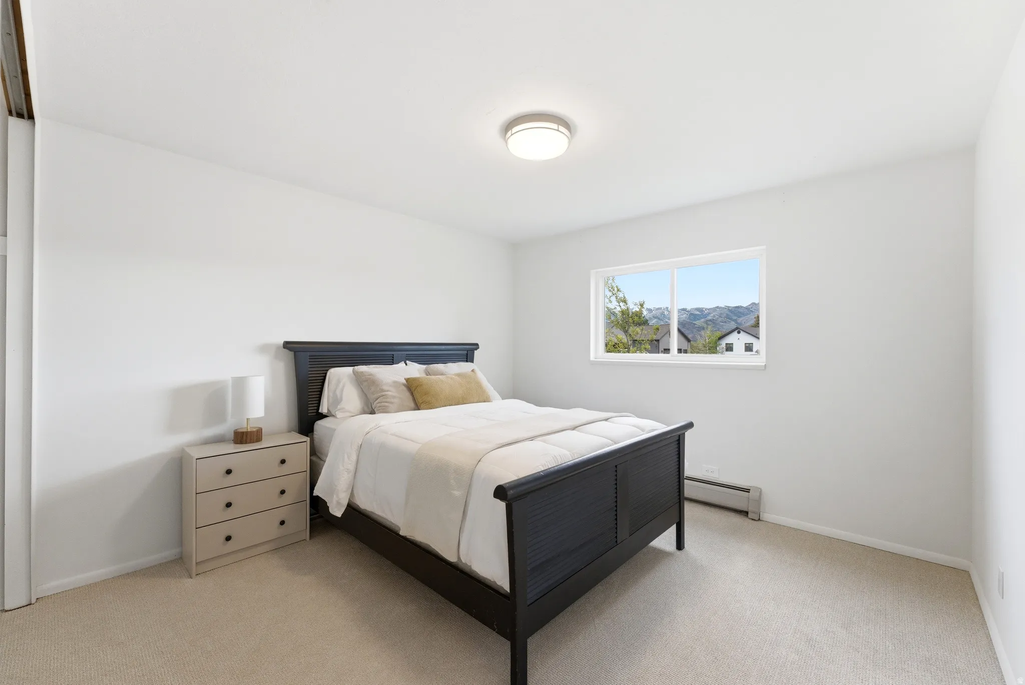 Bedroom with neutral wall color, carpet flooring, a window offering a mountain landscape, and a ceiling-mounted light fixture