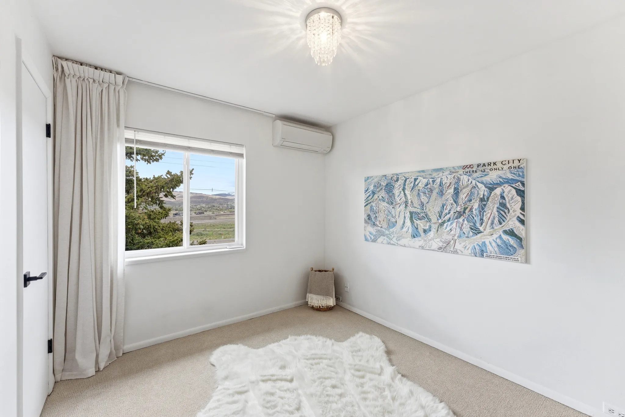 Carpeted room featuring a single window, white walls, and a crystal flush mount ceiling light