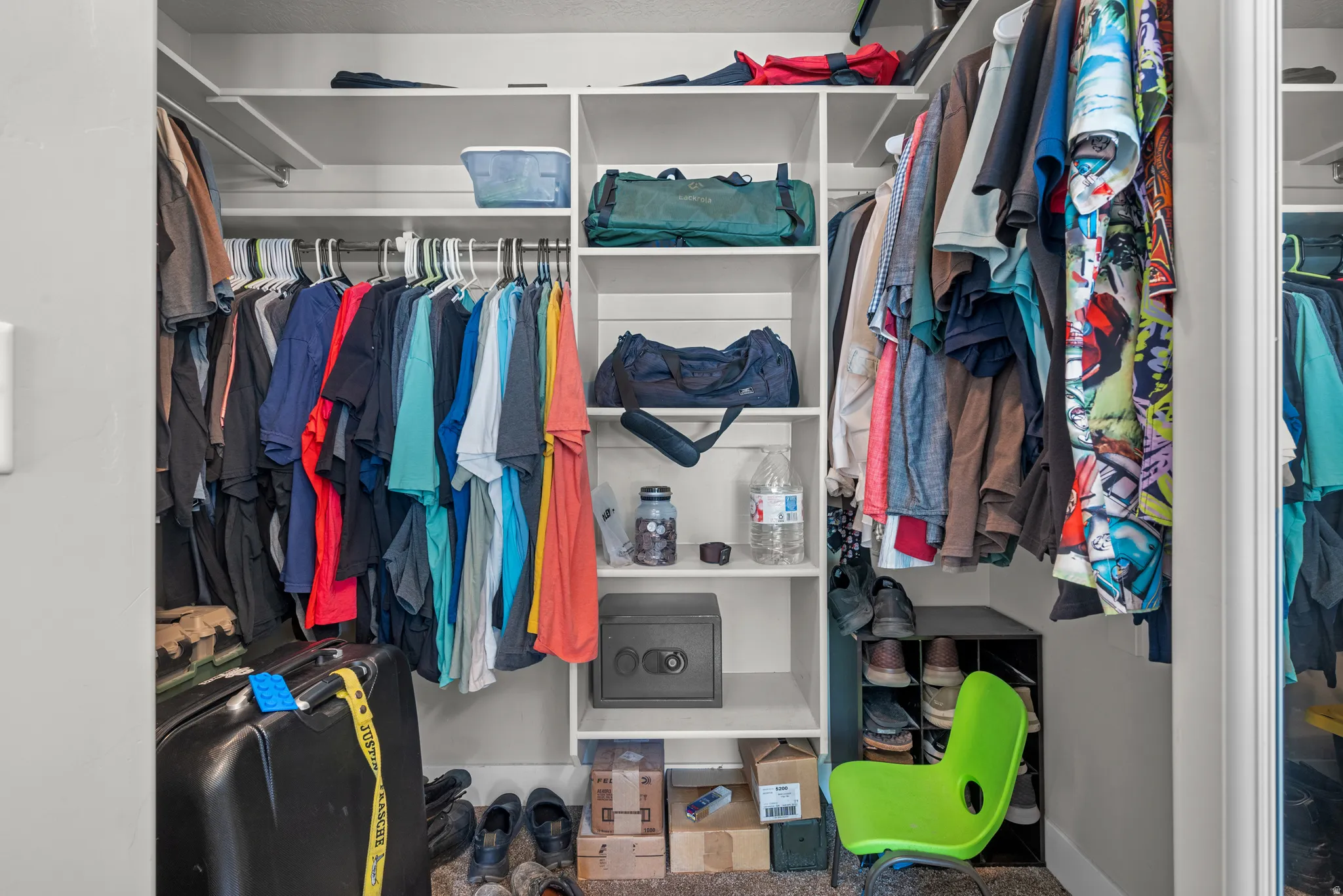 Walk-in closet featuring white built-in shelving, multiple hanging rods, corner shelving units, and a full-length mirror