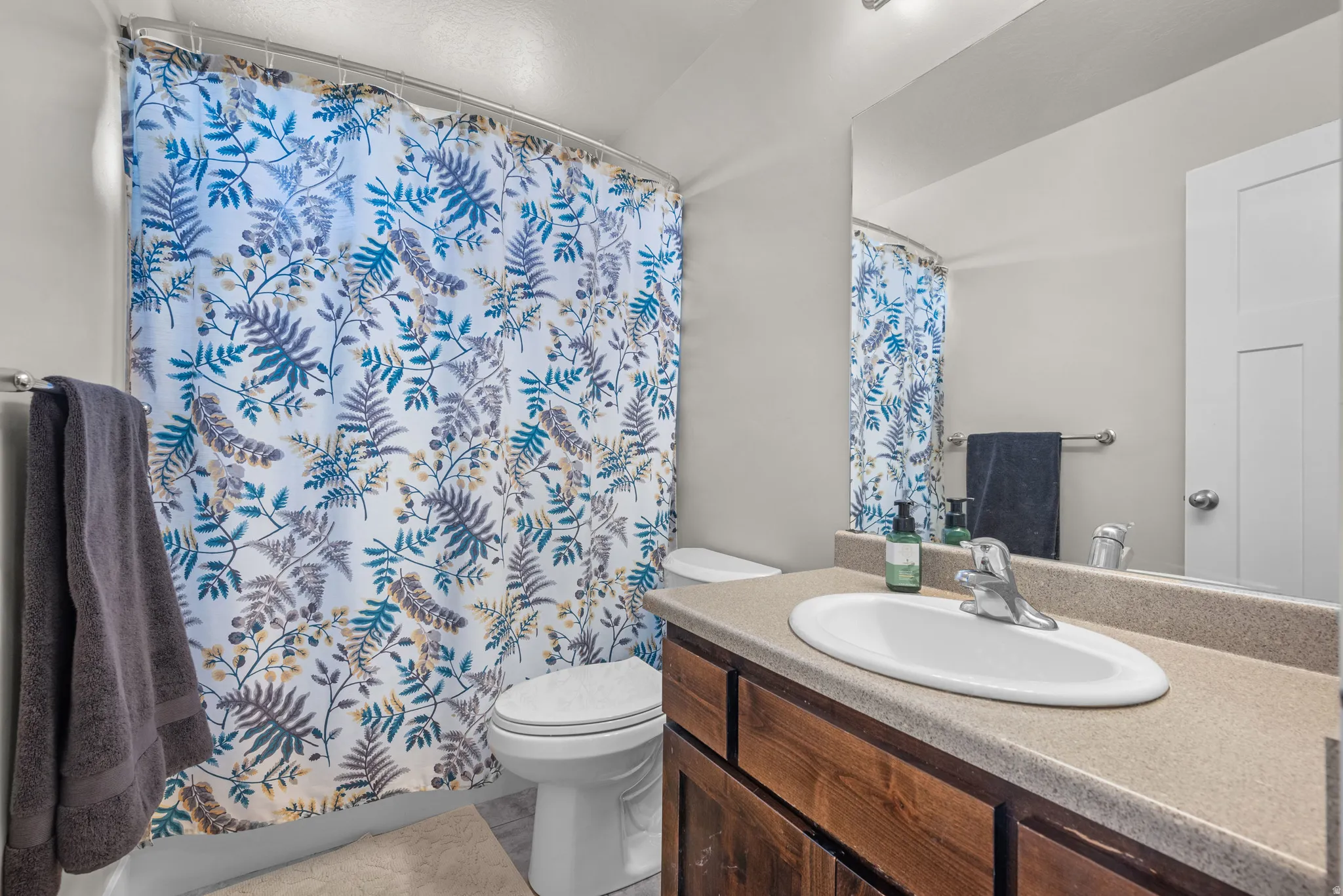 Bathroom featuring a built-in wood-finish vanity with an integrated sink and chrome faucet, a wall-mounted mirror, and a white toilet