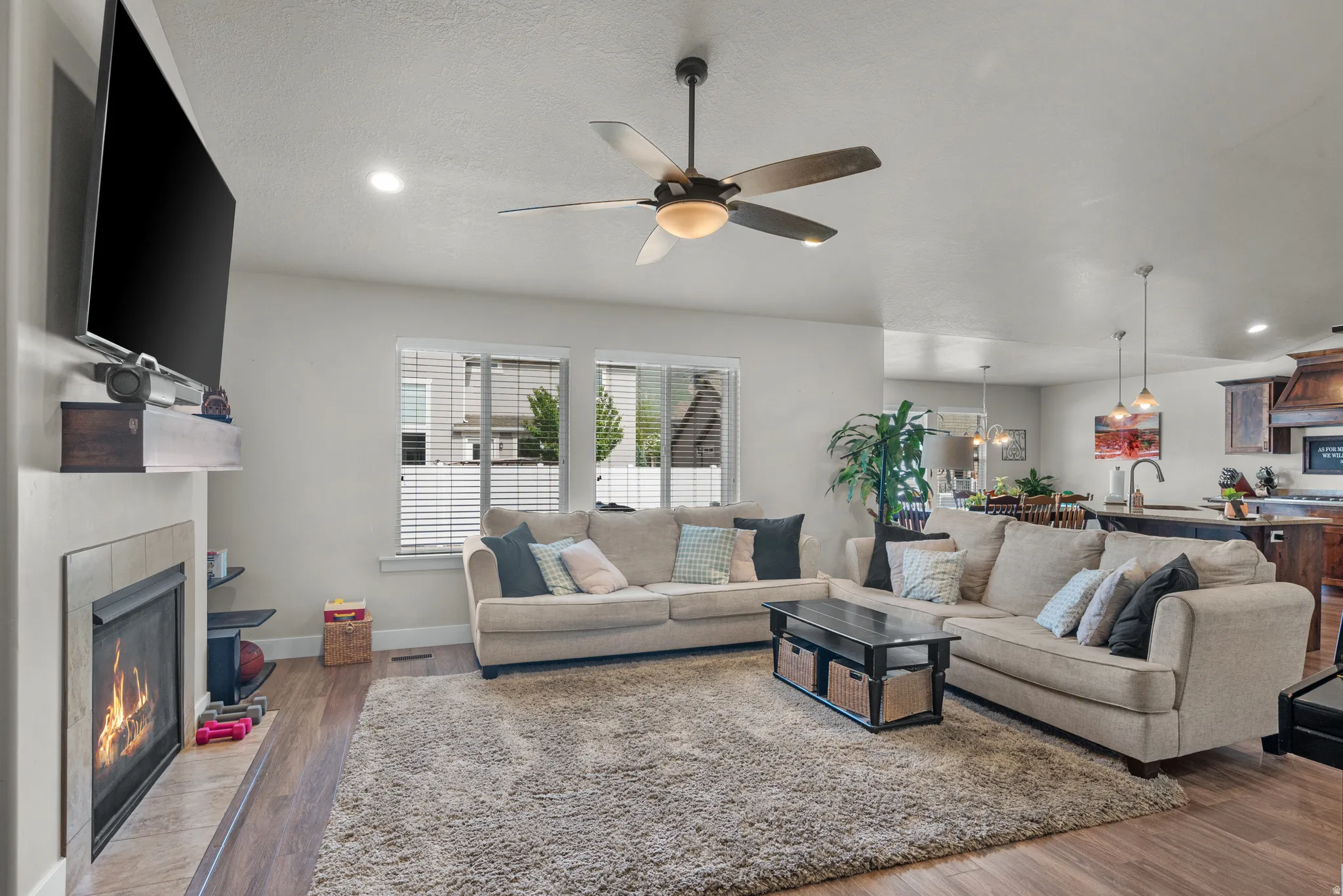 Living area featuring a fireplace with a tile surround, wood-finish flooring, recessed lighting, and a ceiling fan