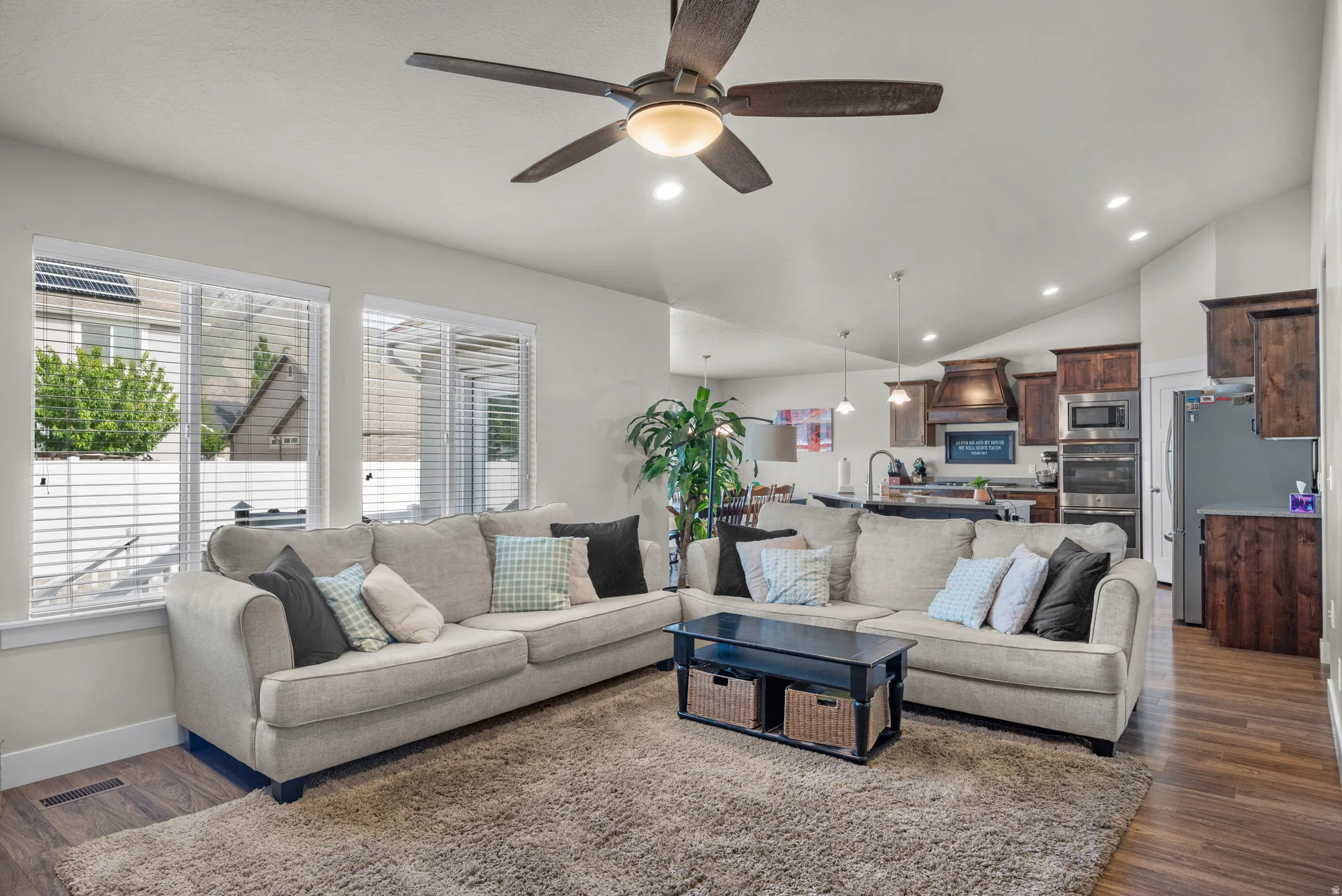 Open-concept living area featuring vaulted ceilings, wood-finish flooring, and recessed lighting