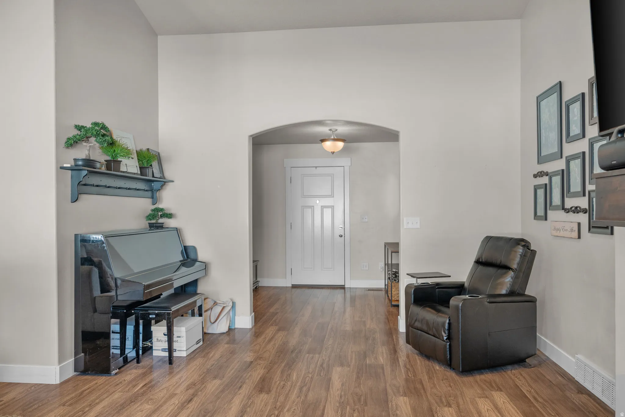 Spacious entry area with wood-finish flooring and an arched doorway