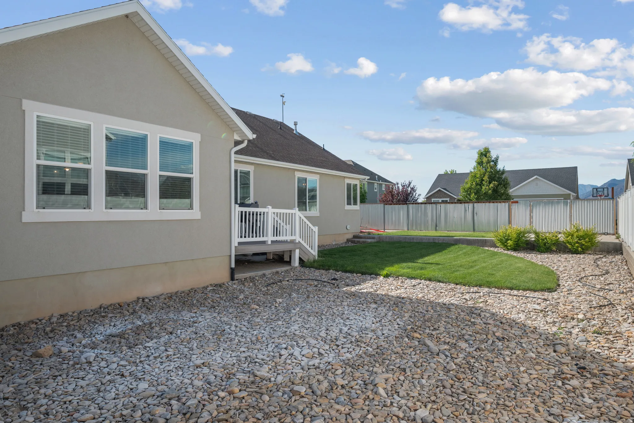 Landscaped backyard featuring an artificial turf lawn, decorative gravel, and a composite deck with white railings