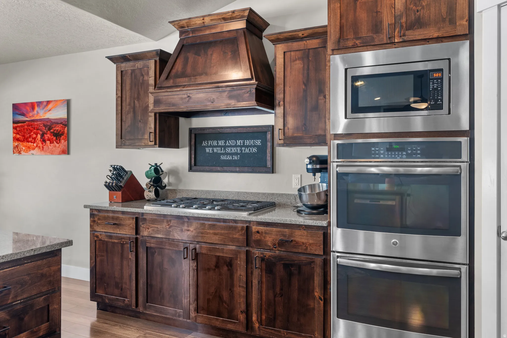 Kitchen featuring dark wood cabinetry, a built-in stainless steel microwave, and double wall ovens