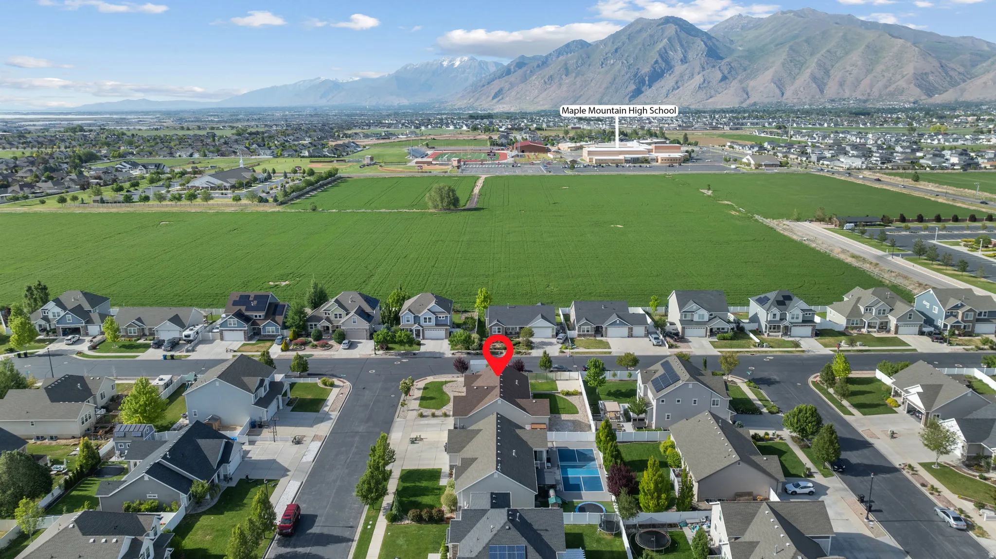Aerial perspective showcasing a residential neighborhood with mountain and field backdrops