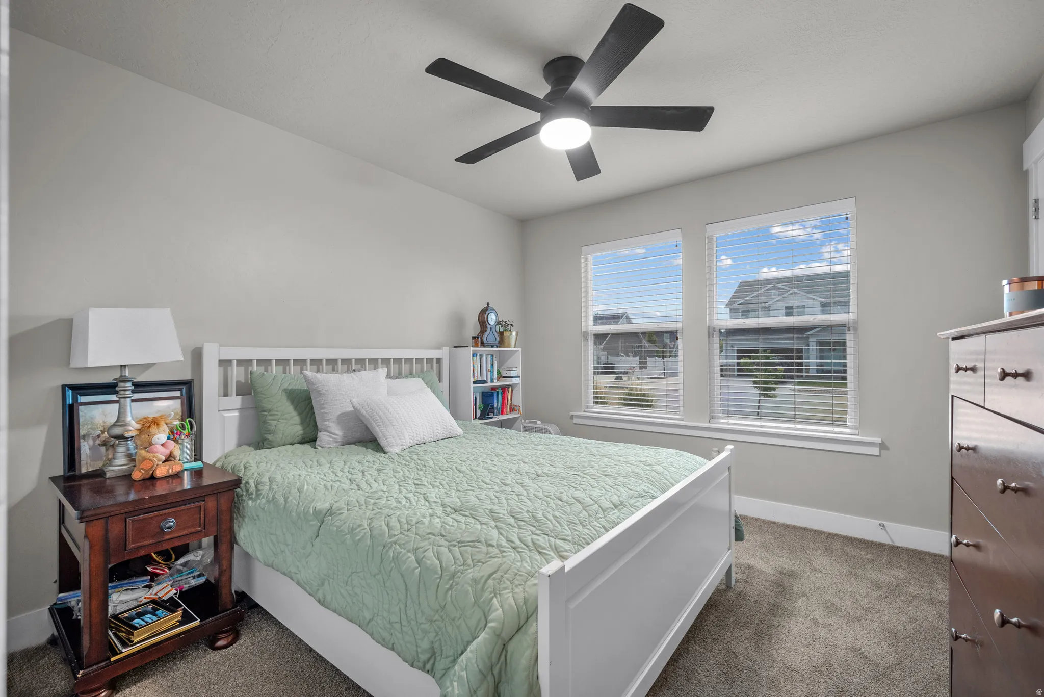 Comfortable bedroom with neutral gray walls and dark gray carpet flooring
