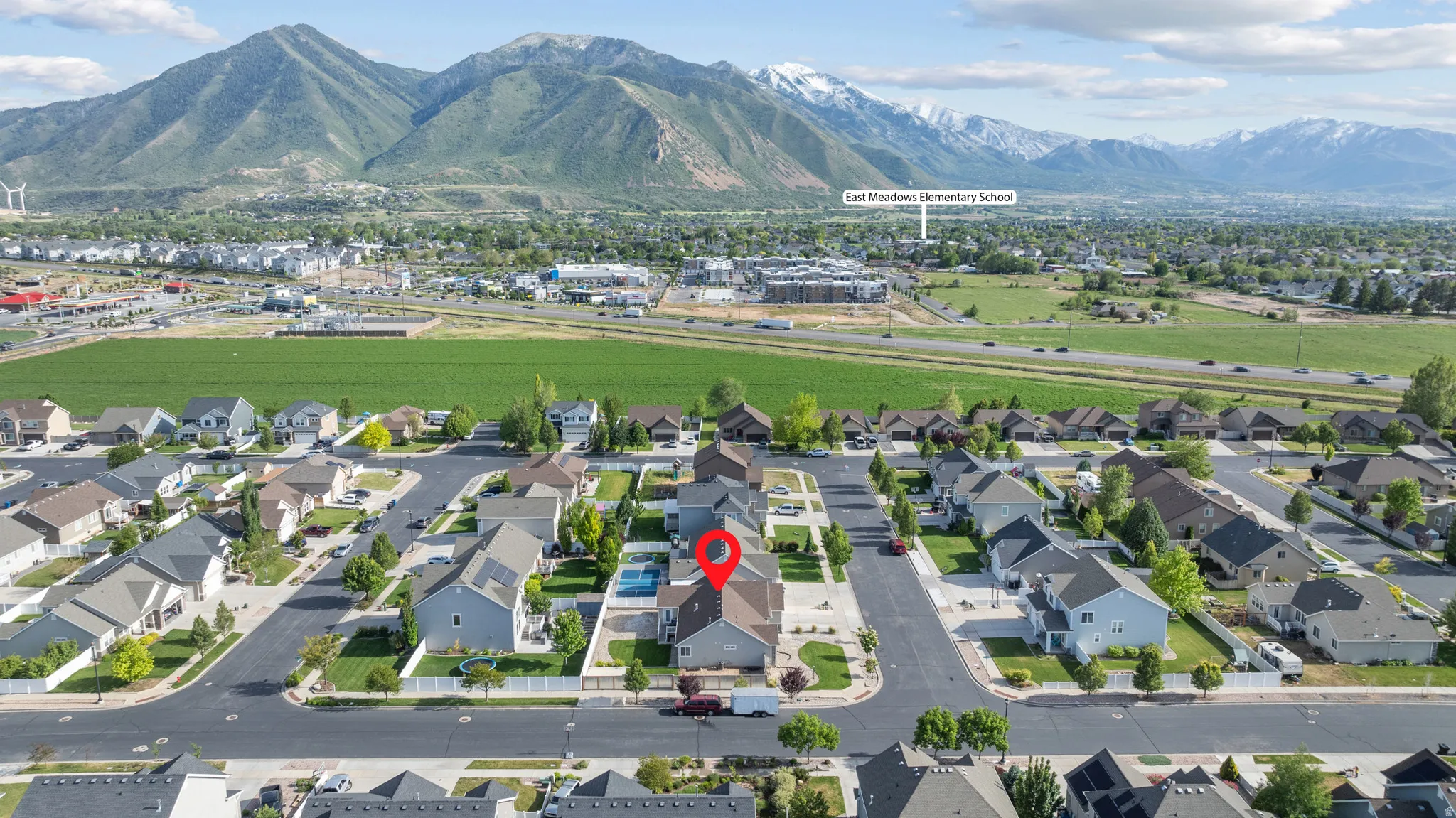 Aerial perspective showcasing a residential neighborhood with mountain backdrops and a visible elementary school