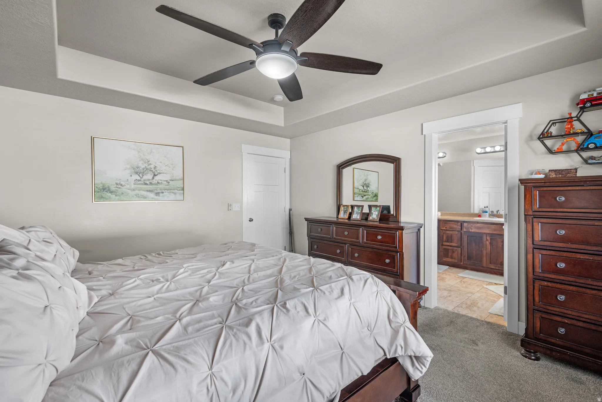 Bedroom featuring a tray ceiling with a ceiling fan, light-toned walls, and grey carpeting