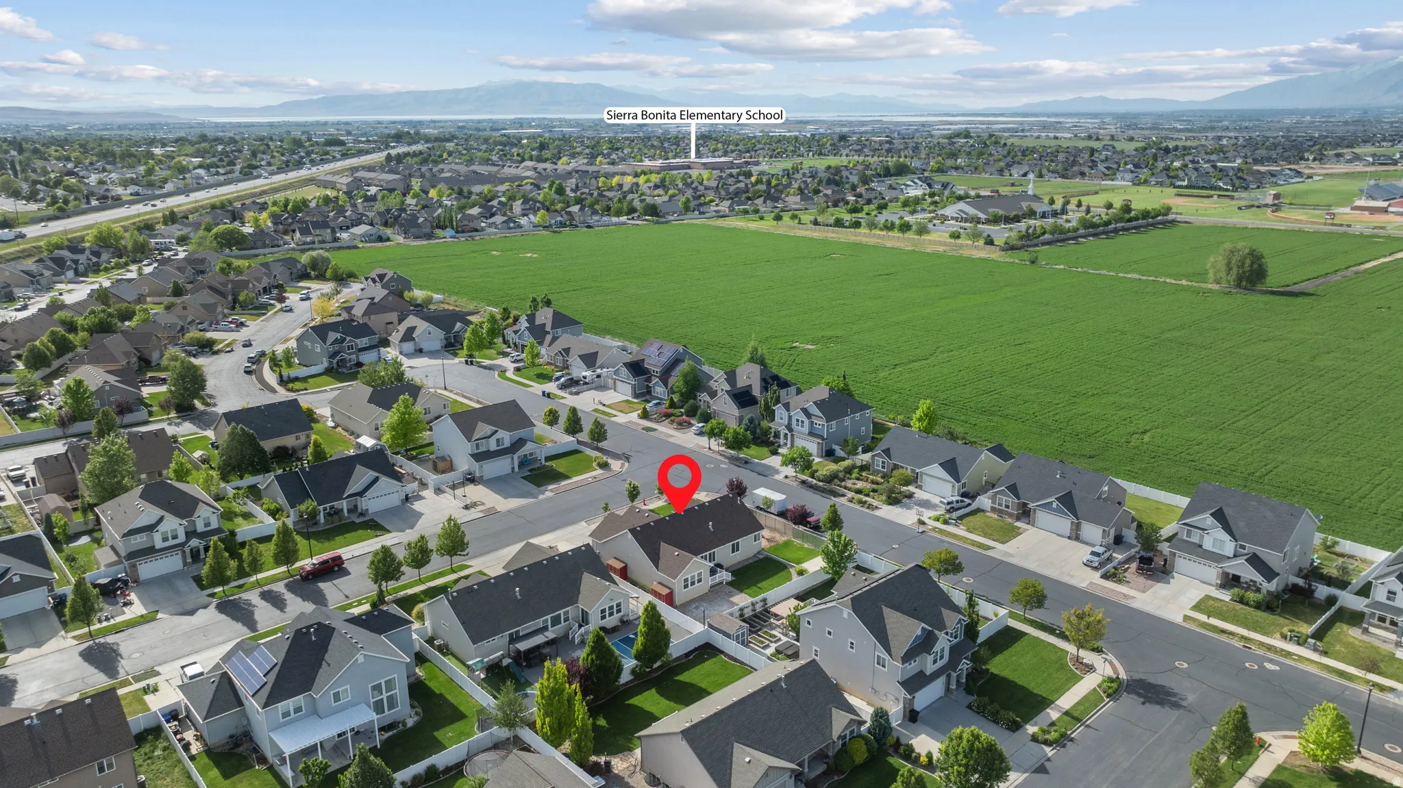 Aerial perspective showcasing a residential neighborhood with surrounding green fields and distant mountains