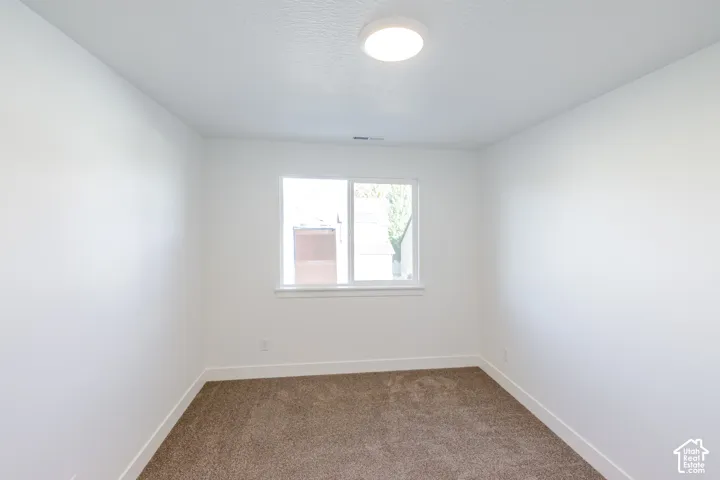 Carpeted flooring, white walls, white window frame, and overhead flush-mount lighting