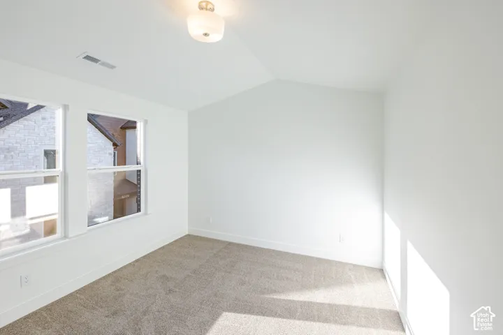 Vaulted ceiling, recessed lighting, double windows, white trim, and neutral carpet
