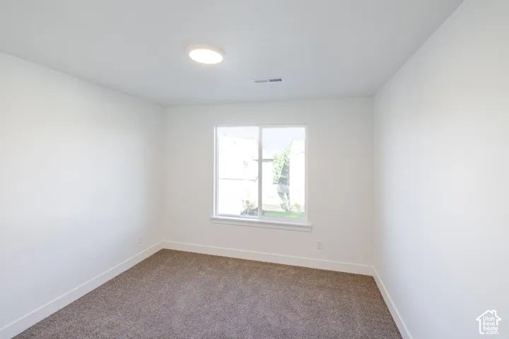 Recessed ceiling light fixture, neutral carpeting, white interior walls, and a window with white trim