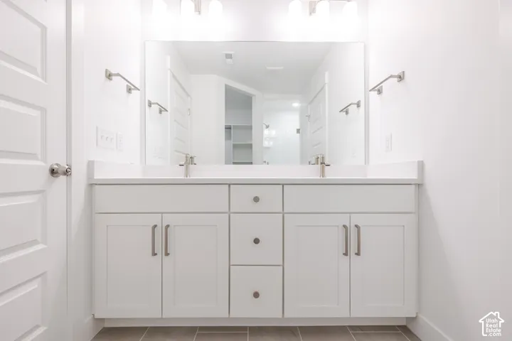 Dual vanity with white shaker-style cabinetry, a light-toned countertop, brushed nickel hardware, and a large wall-mounted mirror