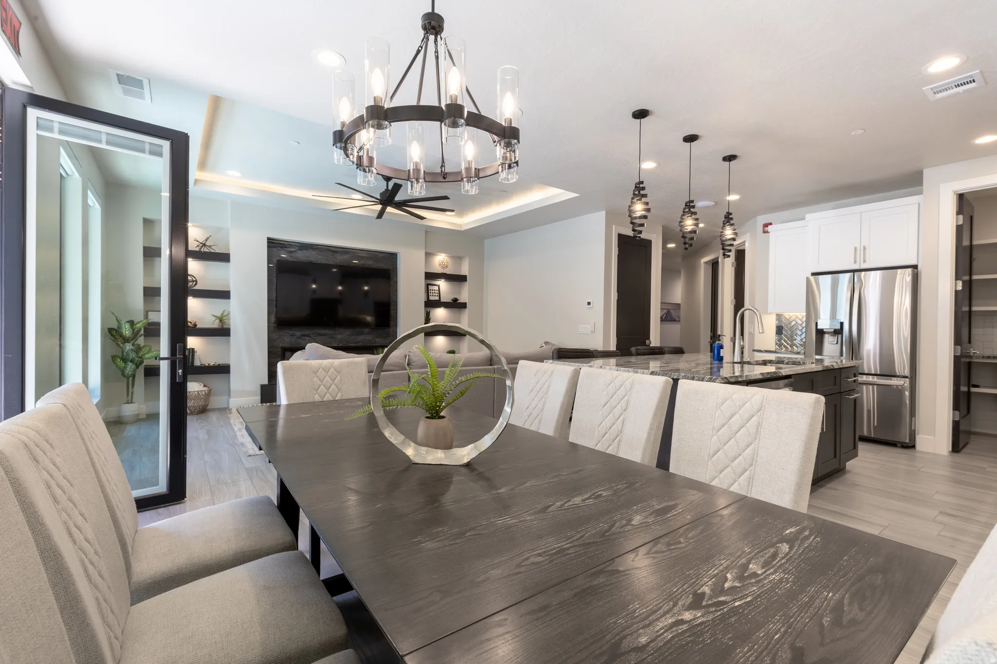 Spacious dining area with a dark wood-finish table, leading to a living room with built-in shelving and a contemporary fireplace