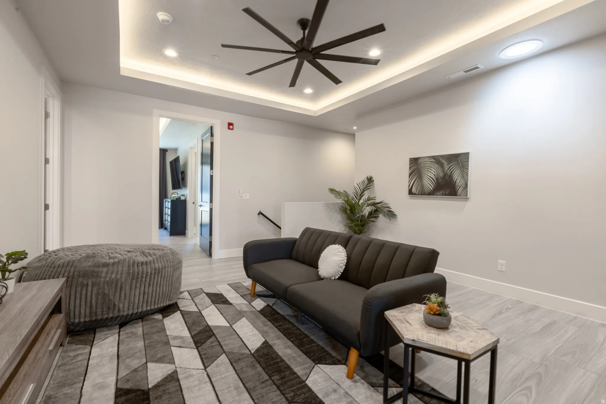 Recessed lighting and a contemporary ceiling fan illuminate this interior space featuring light wood-finish flooring