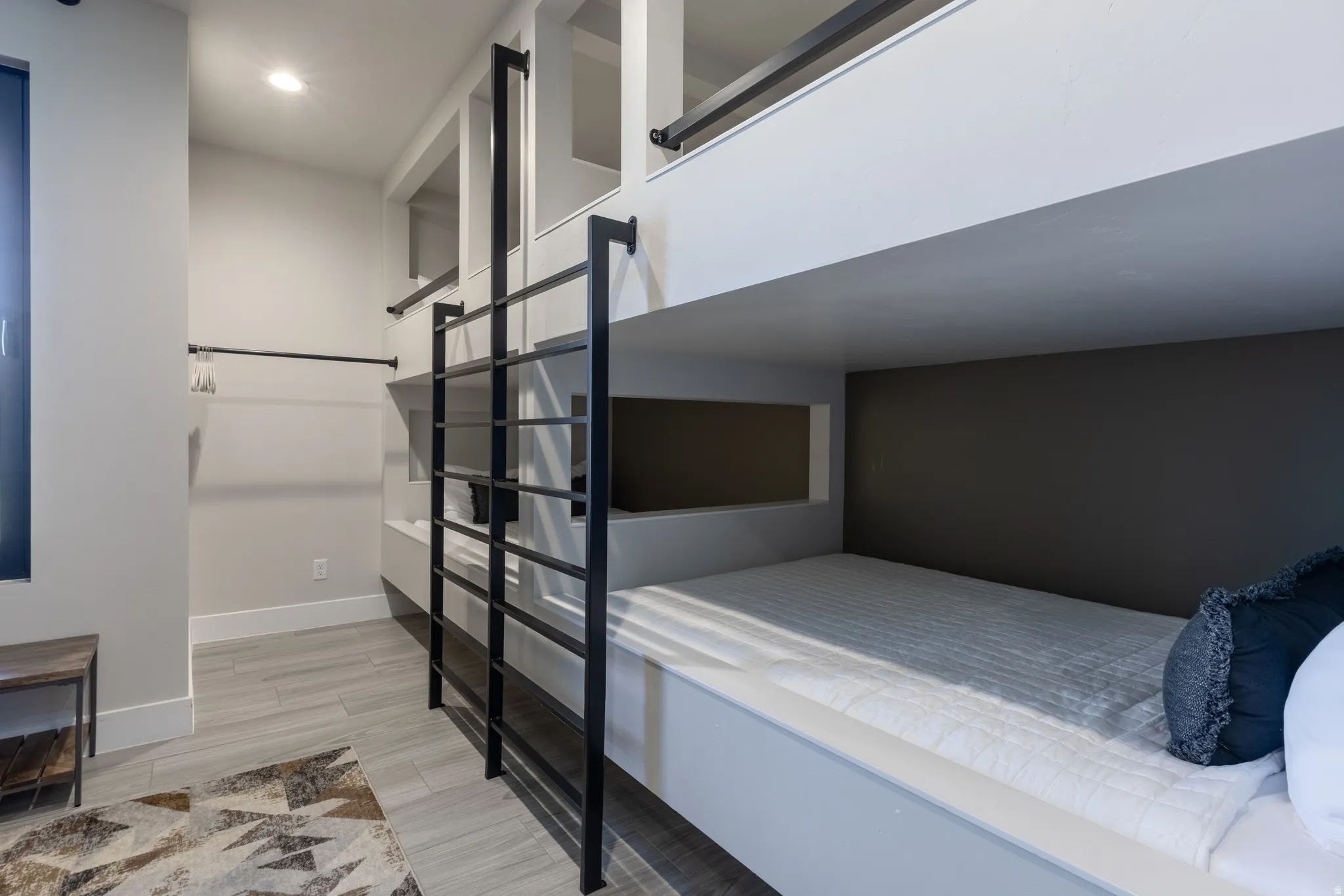 Built-in bunk beds with integrated shelving and black metal ladders