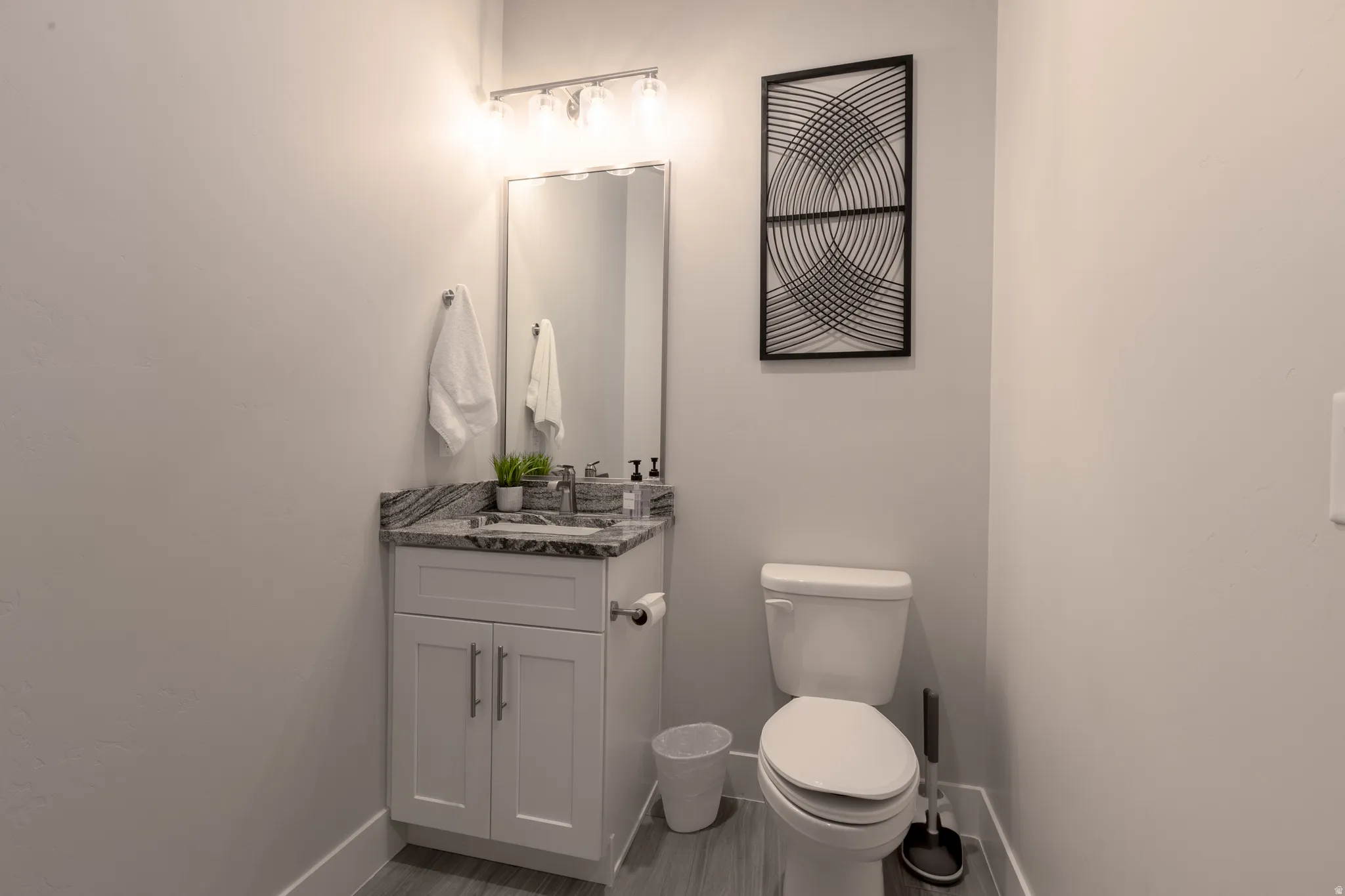 Bathroom featuring a white vanity with a granite countertop, undermount sink, and chrome faucet