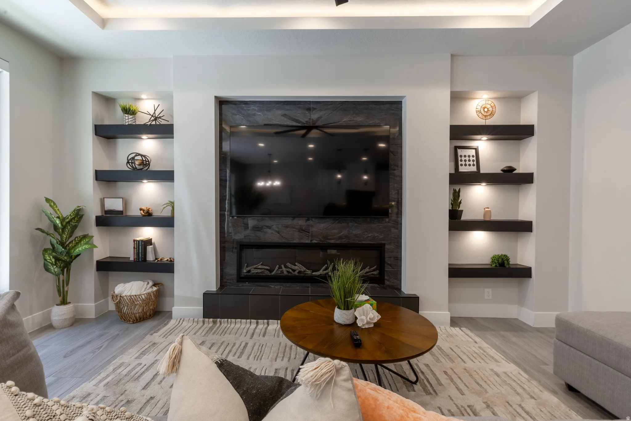 Living area featuring a stone-clad fireplace and media wall with an integrated electric fireplace