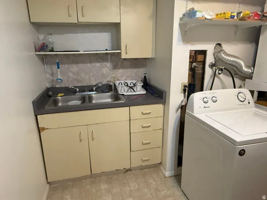 Utility area featuring a double-basin sink, laminate countertop, and overhead cabinetry