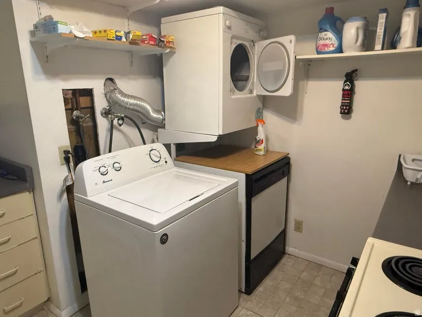 Laundry area featuring a stacked washer and dryer, adjacent to a dishwasher with a wood-finish countertop