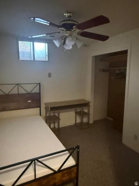 Bedroom featuring a ceiling fan with integrated lighting, a window, and carpeted flooring