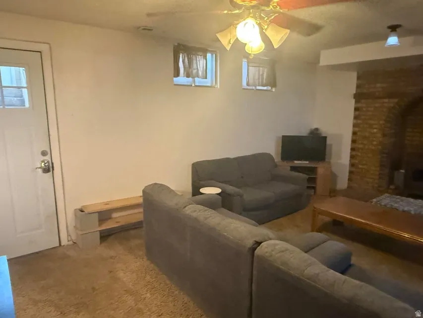 Living area featuring a brick archway, wall-mounted light fixture, and ceiling fan with integrated lighting