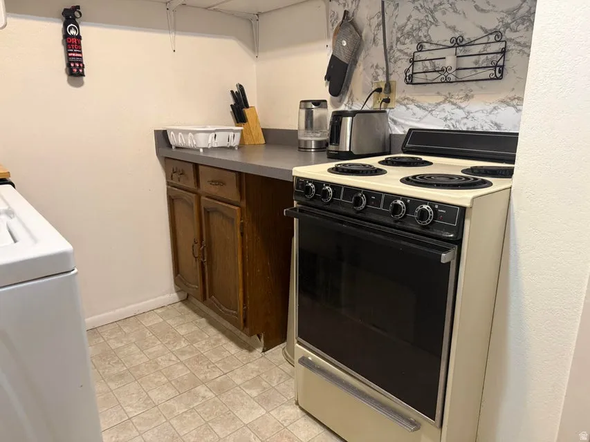 Built-in electric range with four burners and oven, wood cabinetry, and laminate countertop