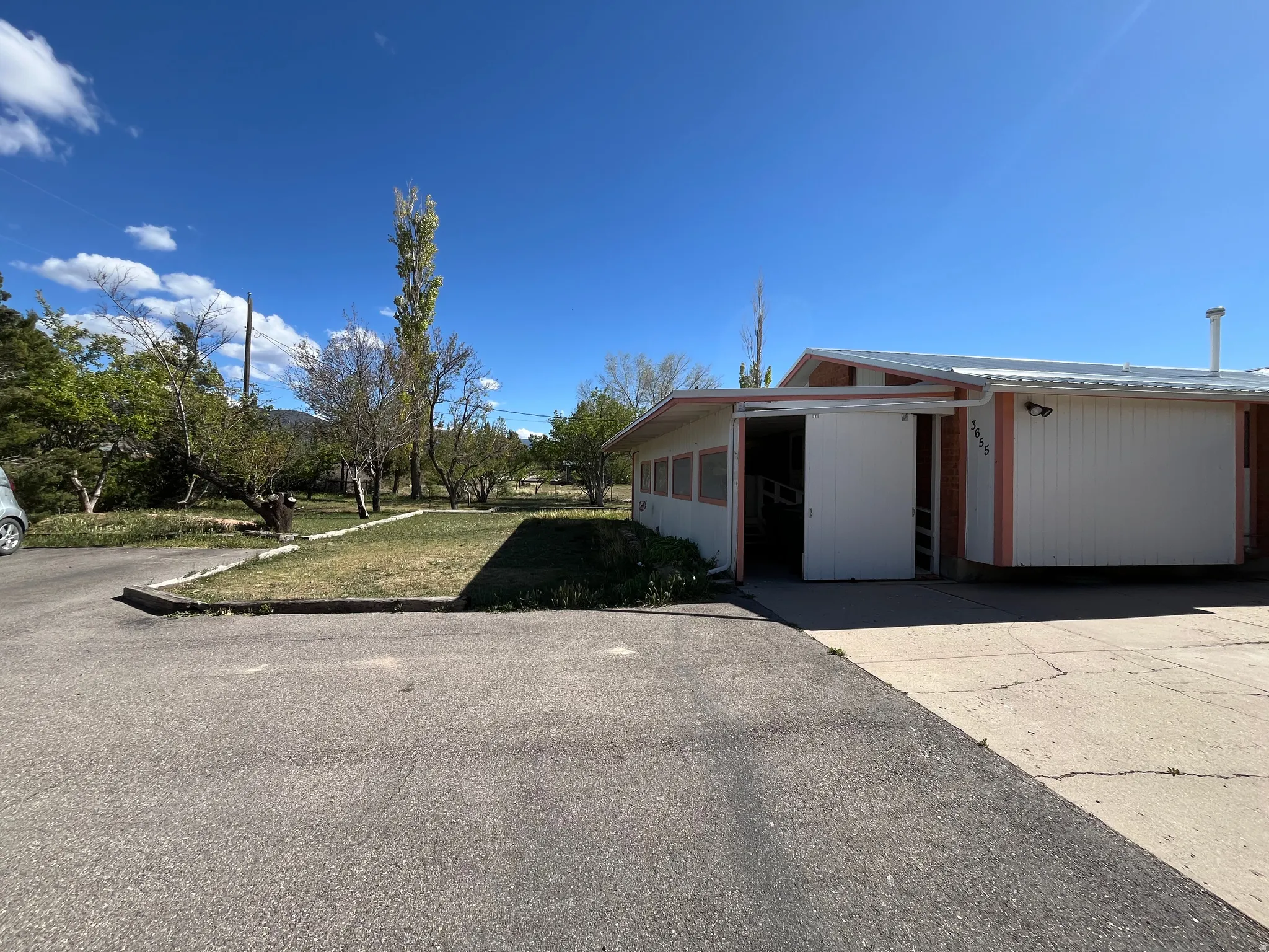 Exterior features include a paved driveway, concrete pad, horizontal siding facade, and multiple windows