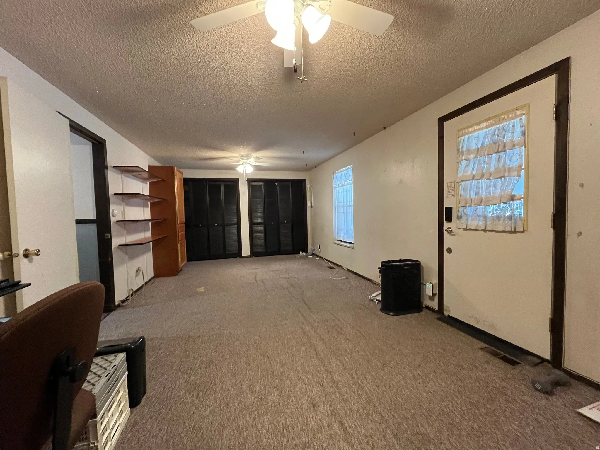 Spacious interior room featuring wall-to-wall carpeting, multiple windows for natural light, and two ceiling fans