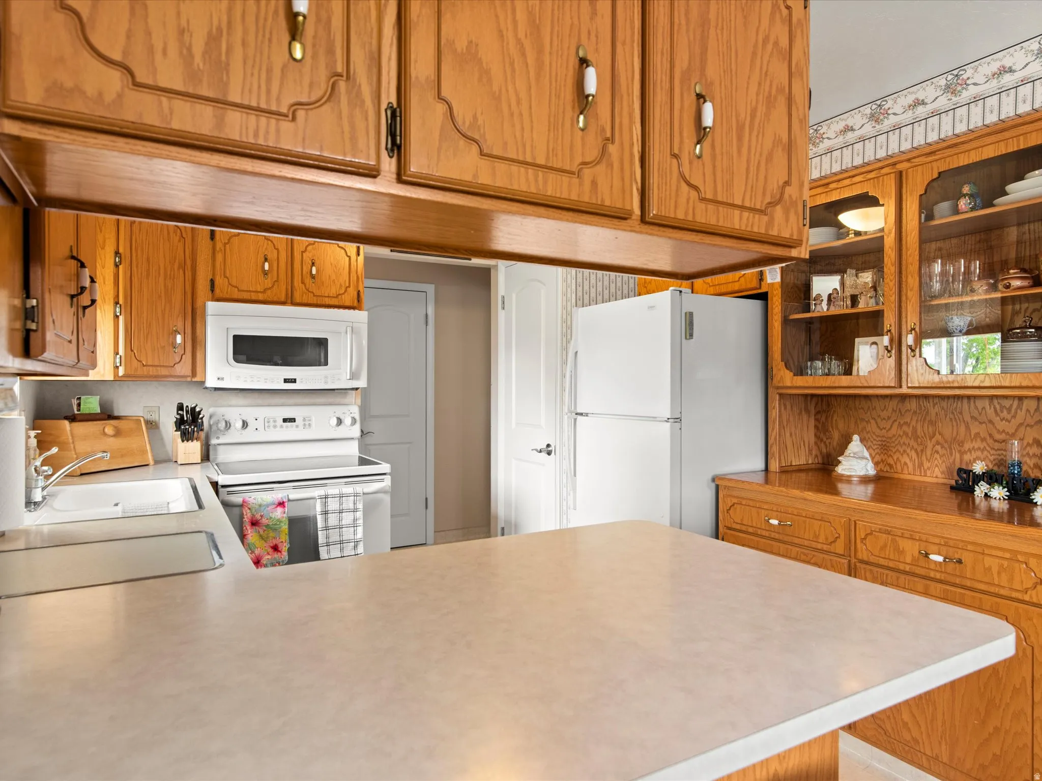 Kitchen featuring wood cabinetry, white appliances, a built-in microwave, and a double-basin sink