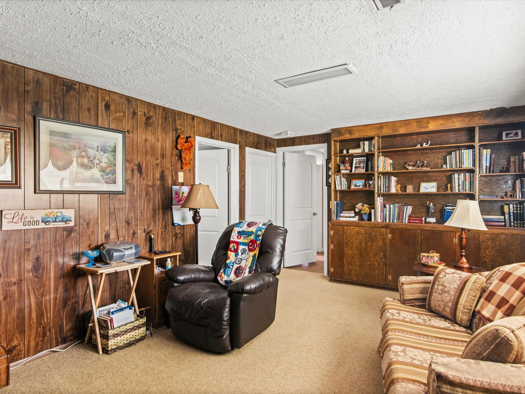 Wood-paneled room featuring extensive built-in shelving, integrated cabinetry, and light-toned carpeting