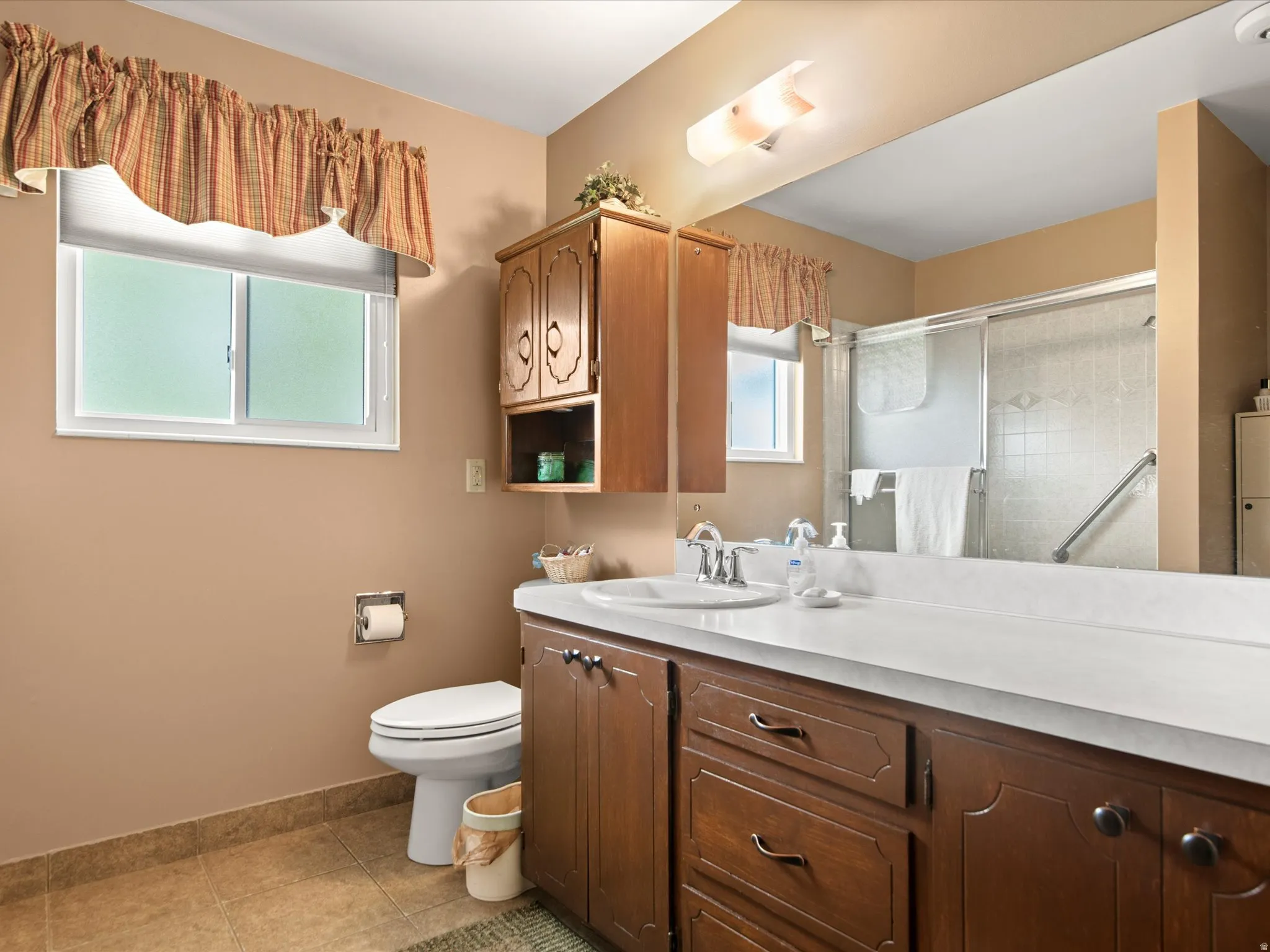 Bathroom featuring a spacious wood-finish vanity with an integrated sink and light-colored countertop